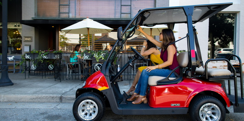 Two women are parked in the red EZ-GO golf cart in front of a restaurant